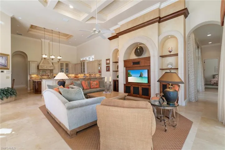 Living room with ceiling fan, a high ceiling, coffered ceiling, ornamental molding, and beamed ceiling