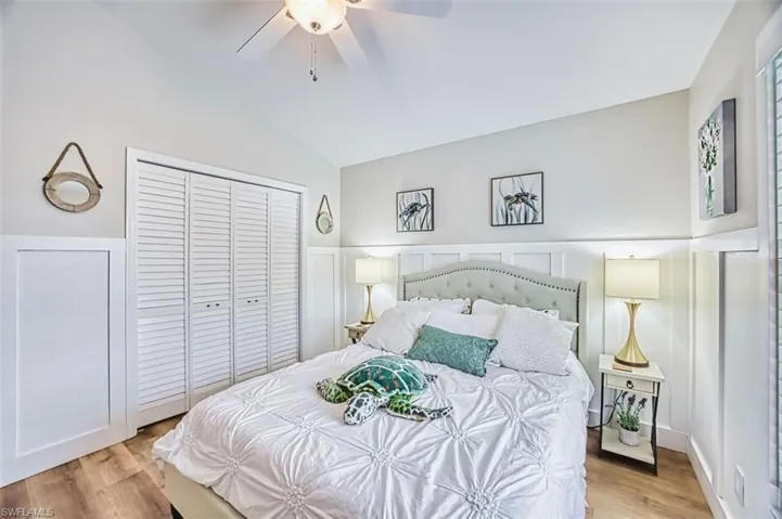 Bedroom with ceiling fan, vaulted ceiling, light wood-style floors, a closet, and a decorative wall