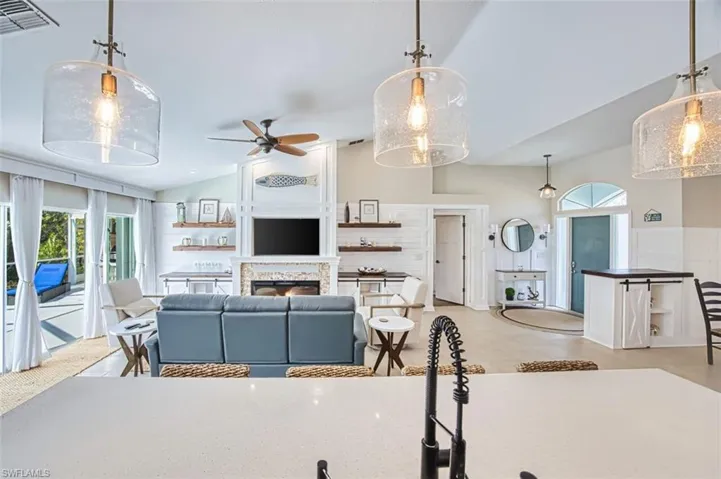 Living area featuring lofted ceiling, a ceiling fan, healthy amount of natural light, and a lit fireplace
