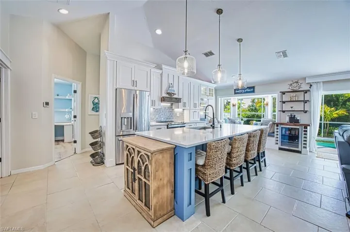 Dual tone kitchen featuring dual tone cabinetry, a kitchen breakfast bar, stainless steel appliances, a large island with sink, and light tile patterned flooring
