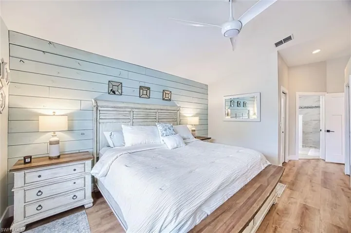 Bedroom featuring light wood-style flooring, connected bathroom, a ceiling fan, wooden walls, and recessed lighting