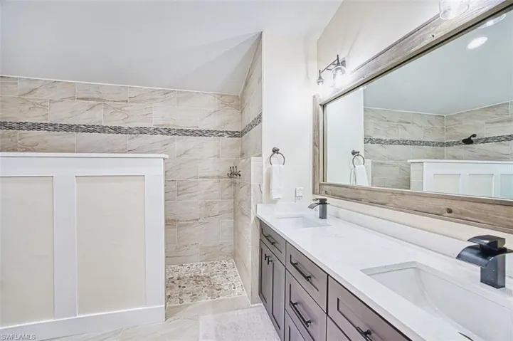 Bathroom featuring a walk in shower and double vanity