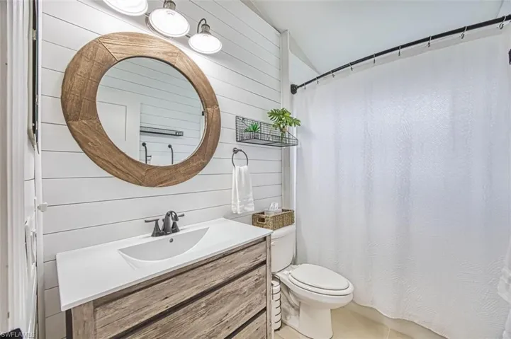 Bathroom featuring vanity, wooden walls, curtained shower, and light tile patterned floors