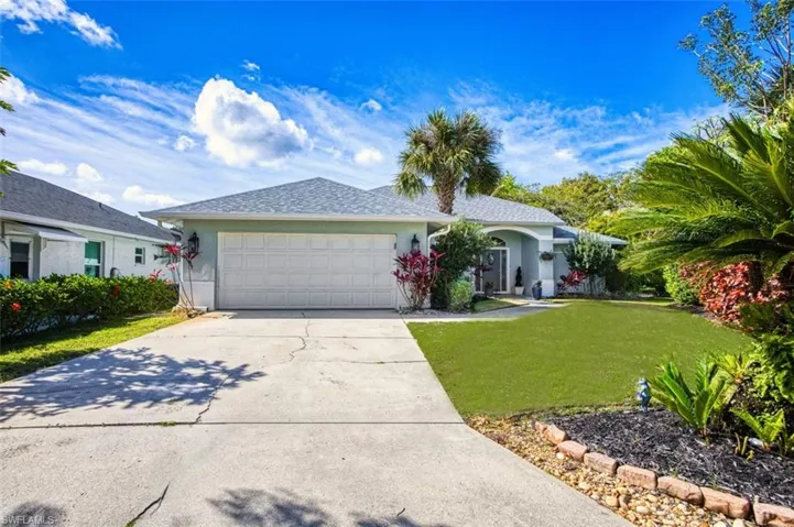 Ranch-style house featuring a front lawn, an attached garage, driveway, and stucco siding