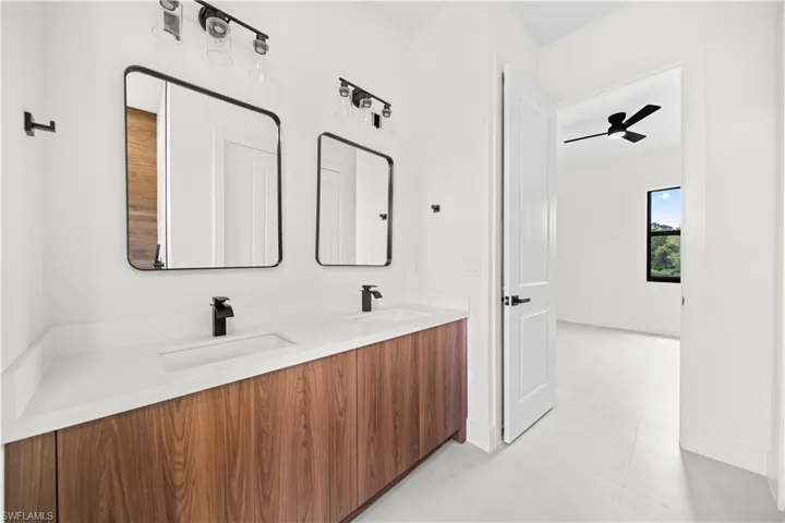 Full bathroom featuring double vanity and ceiling fan