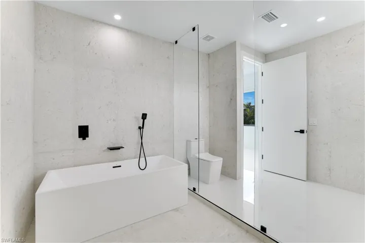 Bathroom featuring recessed lighting, a freestanding tub, visible vents, and toilet