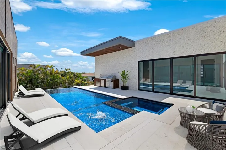 View of swimming pool with grilling area, a patio area, and a pool with connected hot tub