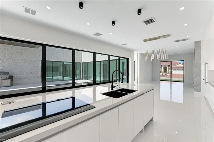Kitchen featuring white cabinets, black electric stovetop, a sink, and visible vents