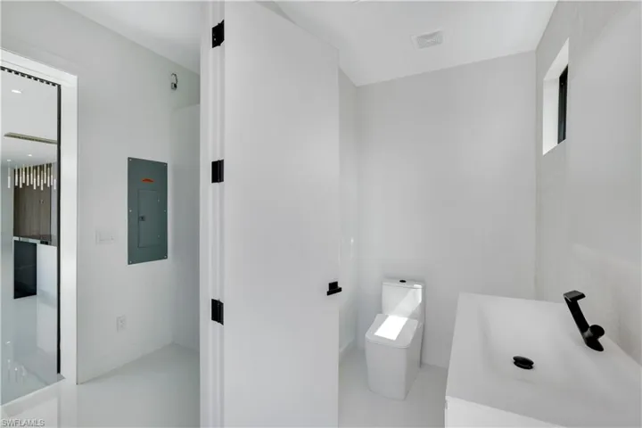 Bathroom with electric panel, visible vents, a sink, and toilet