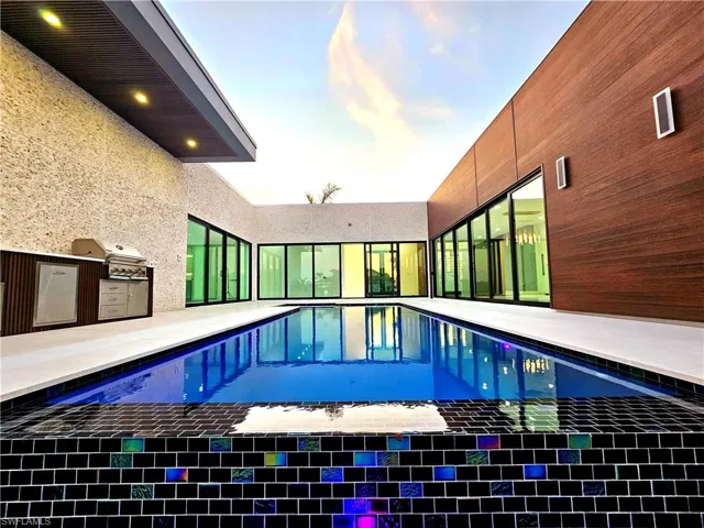 View of swimming pool featuring grilling area, an outdoor kitchen, a patio, and a pool