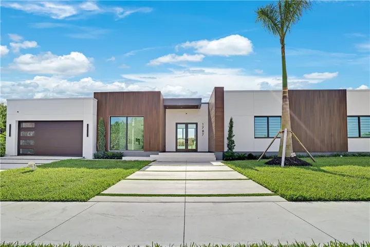 Contemporary house with french doors, an attached garage, a front yard, and stucco siding