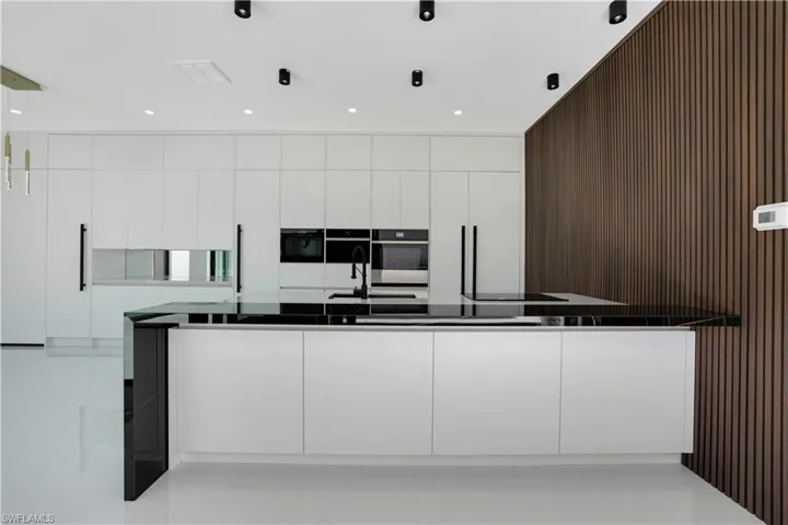 Kitchen with dark countertops, white cabinetry, and modern cabinets