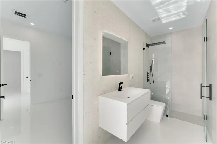 Full bathroom featuring toilet, vanity, visible vents, and a stall shower