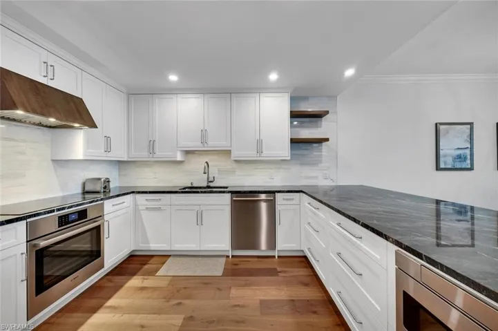 Kitchen with open shelves, white cabinets, stainless steel appliances, dark stone counters, and recessed lighting