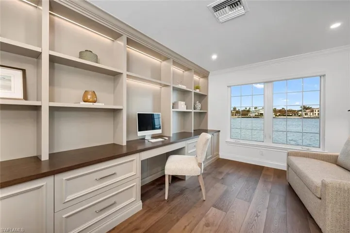 Office area featuring built in desk, dark wood-type flooring, and crown molding
