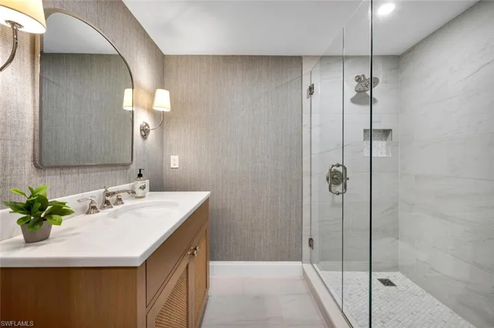 Bathroom featuring vanity, a shower stall, and wallpapered walls