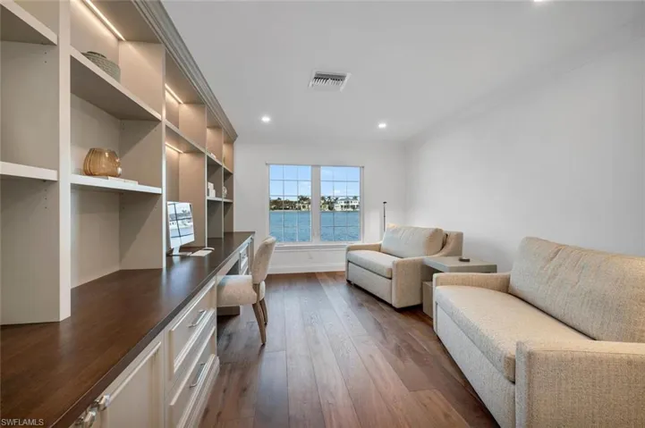 Office featuring built in desk, dark wood-style flooring, ornamental molding, and recessed lighting