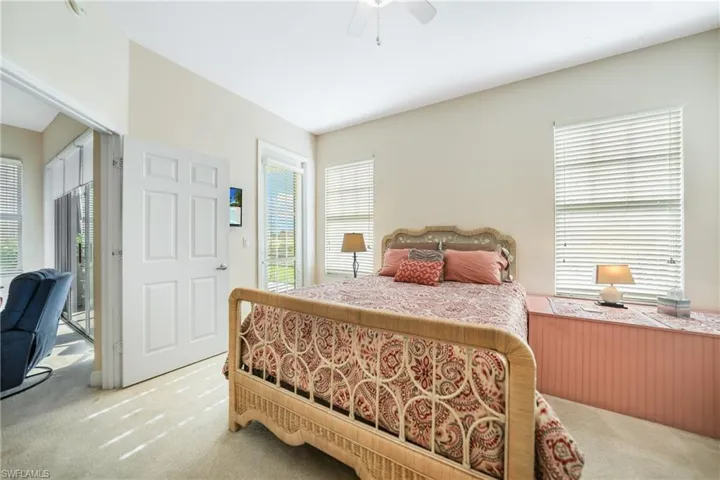 Carpeted bedroom with ceiling fan and multiple windows