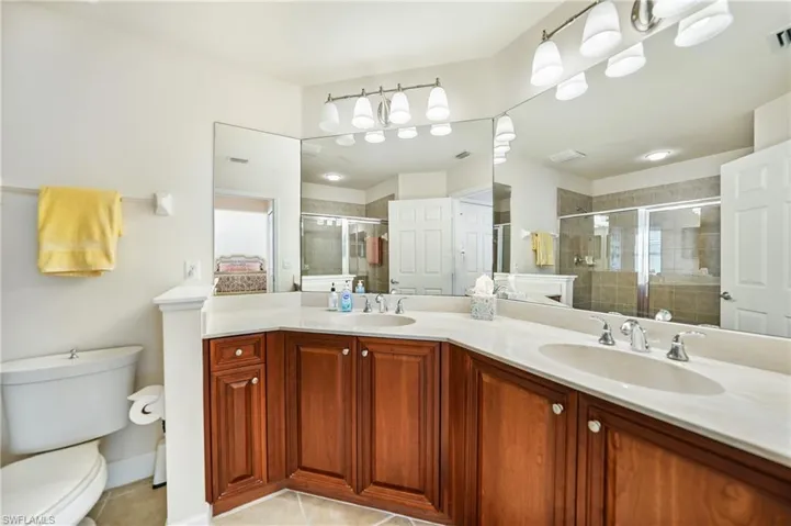 Bathroom featuring a shower with shower door, toilet, vanity, and tile patterned floors
