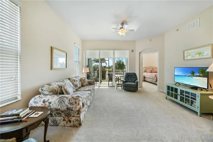 Living room with ceiling fan and light carpet