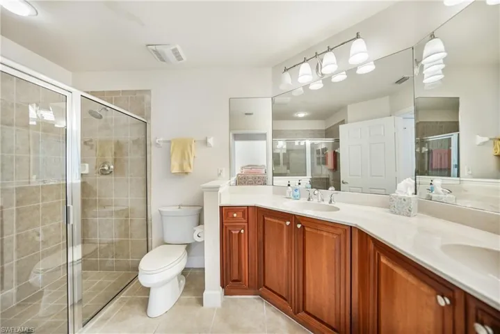 Bathroom with a shower with door, tile patterned floors, toilet, and vanity