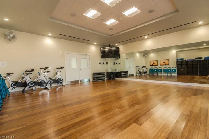 Exercise room with a drop ceiling, a tray ceiling, and hardwood / wood-style flooring