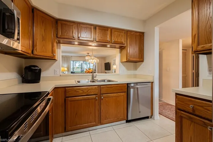Kitchen featuring pendant lighting, stainless steel appliances, an inviting chandelier, sink, and light tile patterned flooring