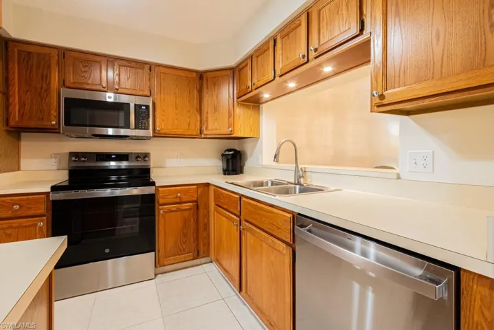 Kitchen featuring light tile patterned floors, sink, and appliances with stainless steel finishes