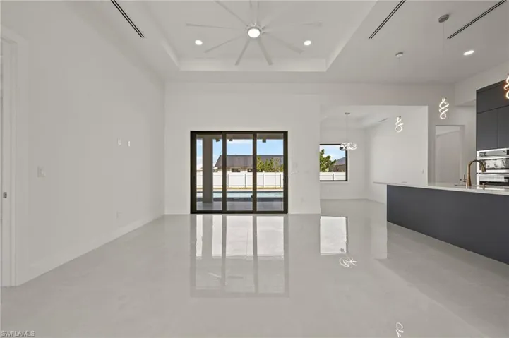 Unfurnished living room featuring recessed lighting, a raised ceiling, a towering ceiling, a sink, and baseboards