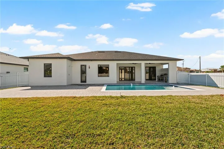 Back of house featuring a ceiling fan, a patio area, a fenced backyard, and a lawn
