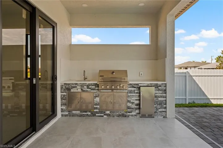 View of patio / terrace with exterior kitchen, a grill, fence, and a sink