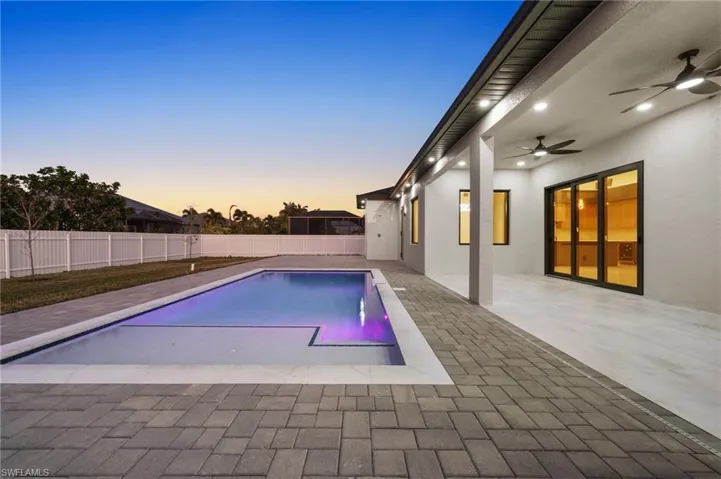 Pool at dusk featuring a fenced in pool, a patio area, a fenced backyard, and ceiling fan