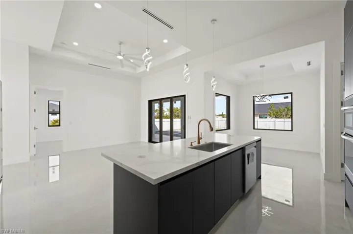 Kitchen featuring dark cabinets, a raised ceiling, a sink, and open floor plan