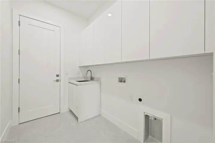 Washroom featuring cabinet space, baseboards, hookup for a washing machine, electric dryer hookup, and a sink