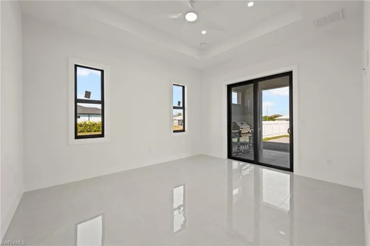 Empty room with a tray ceiling, recessed lighting, visible vents, ceiling fan, and baseboards