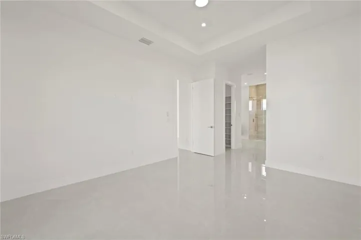 Empty room featuring a tray ceiling, visible vents, baseboards, and recessed lighting