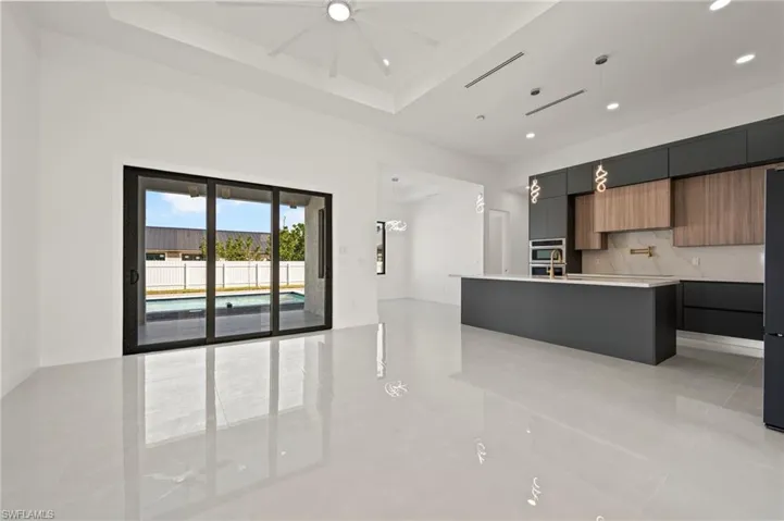 Kitchen with light countertops, tasteful backsplash, modern cabinets, and a center island with sink