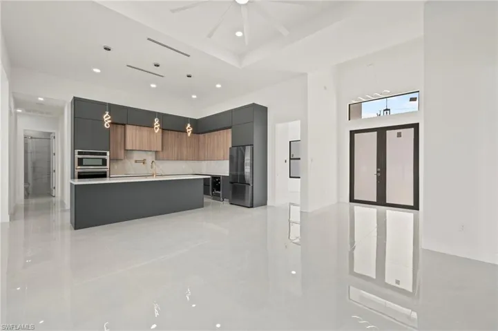 Kitchen with a kitchen island with sink, a sink, light countertops, freestanding refrigerator, and modern cabinets