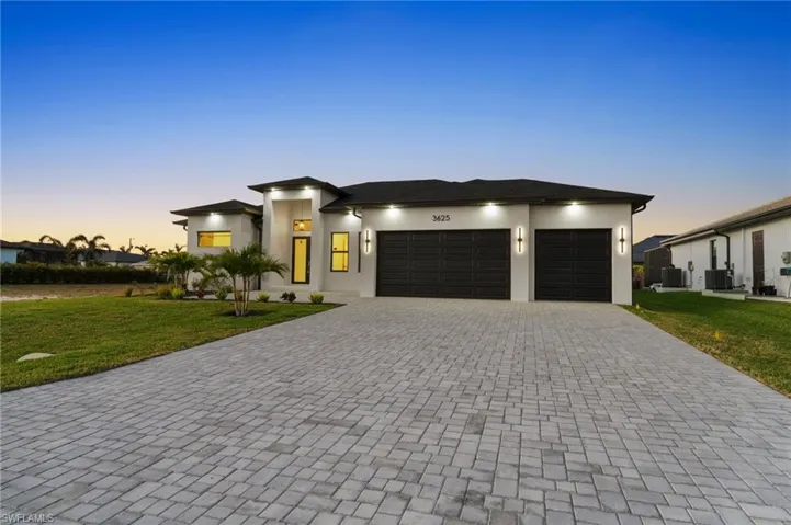 View of front of property featuring decorative driveway, a front lawn, and stucco siding