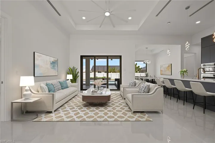 Living room with a high ceiling, a raised ceiling, and recessed lighting