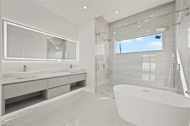Bathroom featuring double vanity, a freestanding tub, a shower stall, and a sink