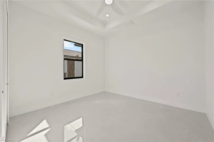 Empty room featuring baseboards, a raised ceiling, ceiling fan, concrete flooring, and recessed lighting