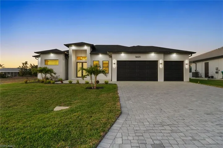 Prairie-style house with decorative driveway, a lawn, an attached garage, and stucco siding