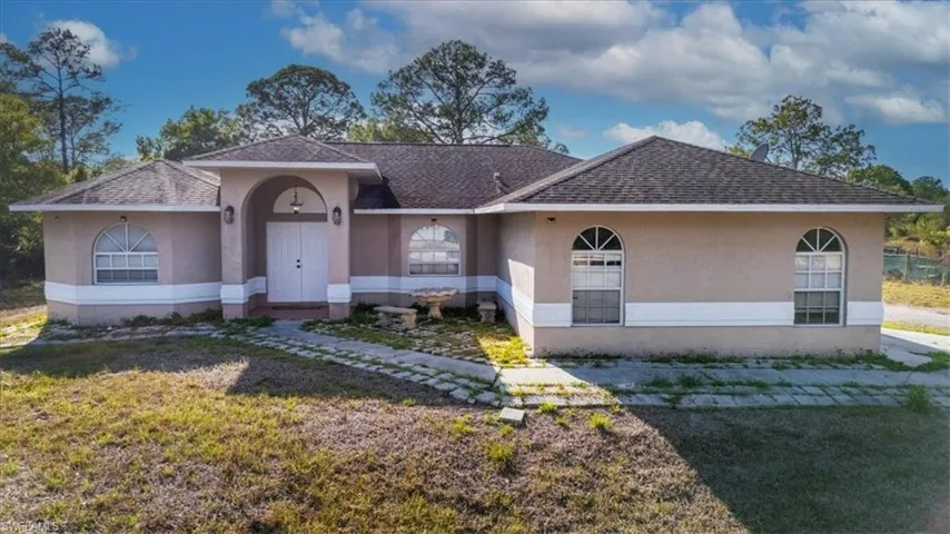 View of front of home with stucco siding, roof with shingles, and a front yard