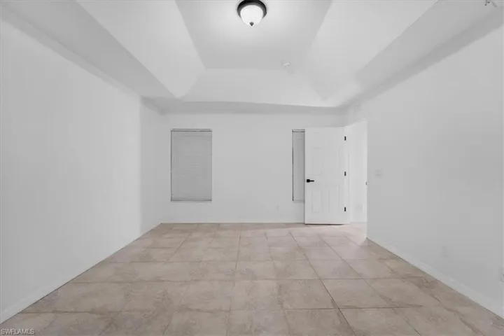 Unfurnished room with a tray ceiling and baseboards
