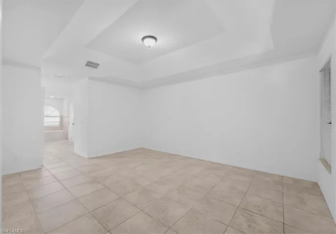 Spare room with a tray ceiling and light tile patterned floors
