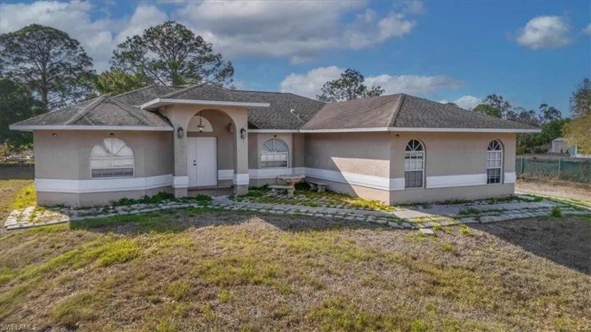 Ranch-style house with stucco siding, a front yard, and a shingled roof