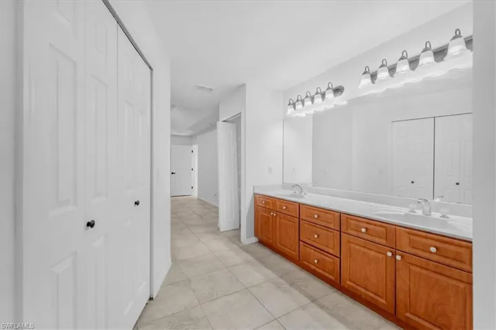 Full bath with a closet, double vanity, and light tile patterned floors