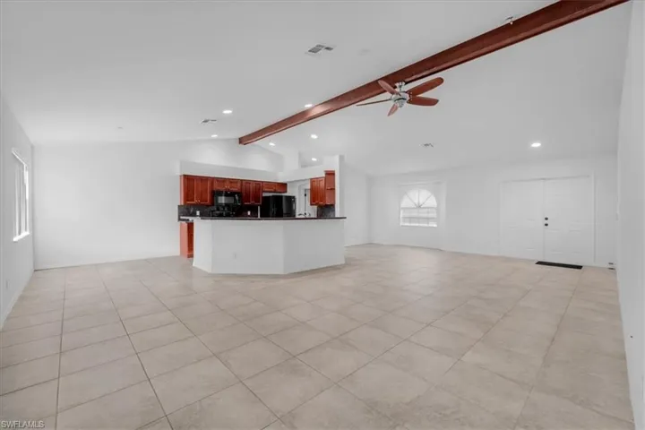 Kitchen with open floor plan, ceiling fan, dark countertops, recessed lighting, and black appliances