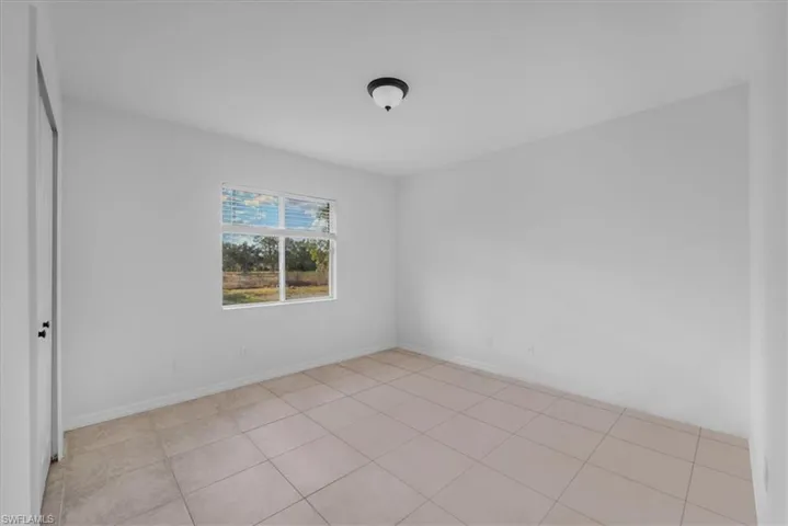 Spare room featuring light tile patterned floors and baseboards
